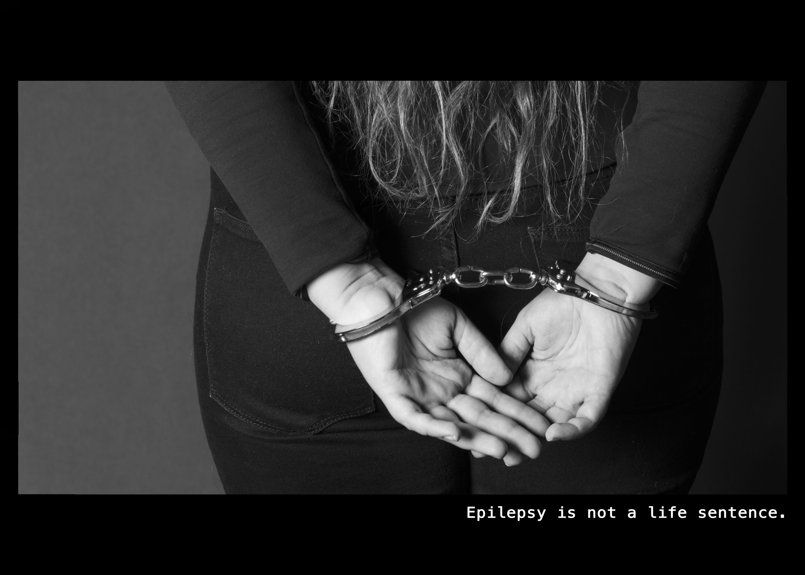 Image of a woman handcuffed with her hands behind her back. Text: Epilepsy is not a life sentence.