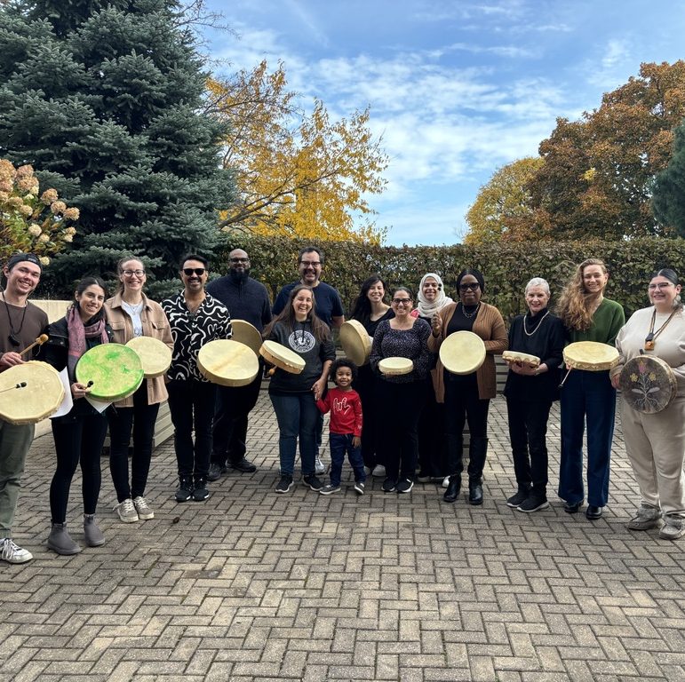 Epilepsy Toronto staff members stand in a circle with facilitators from Native Child and Family Services holding native drums.