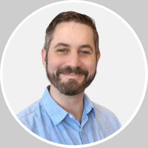 headshot Headshot of Kirk Rabould, wearing a blue shirt, with a beard, smiling to camera.