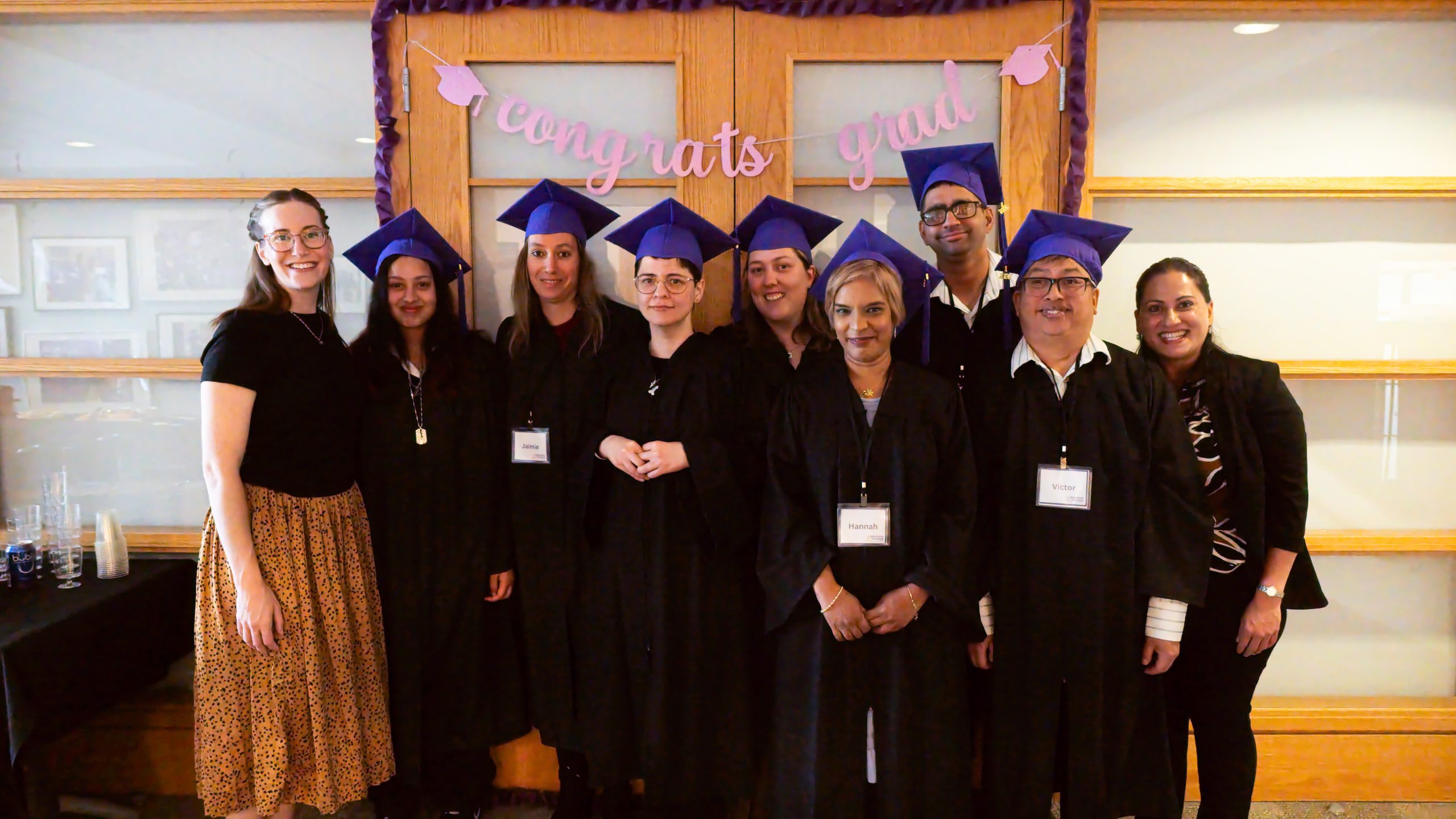 Securing Futures Cohort 4 Grads A group of adults in black robes and purple Graduation hats.